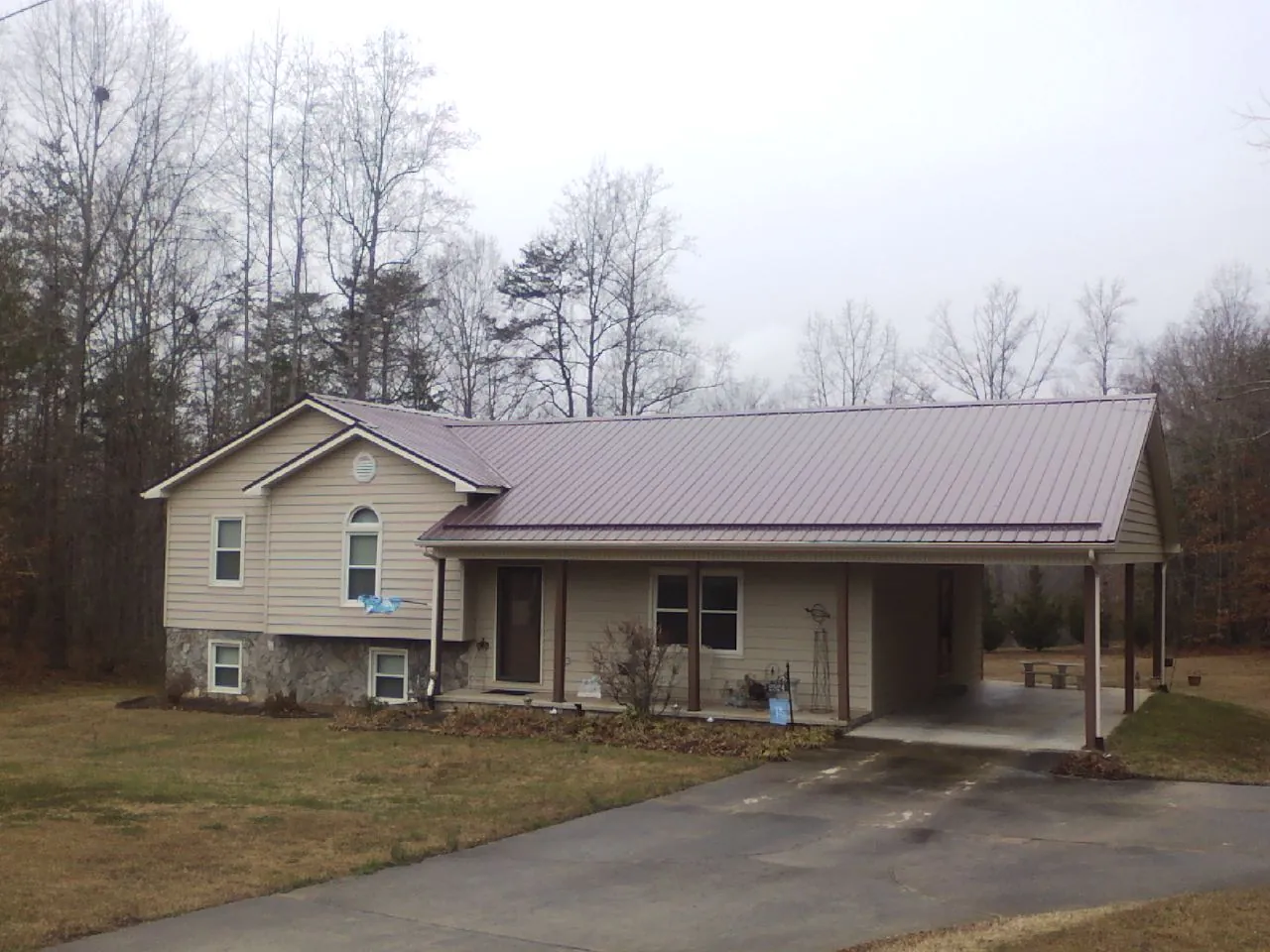 Burgundy metal roof on a tan split level home with an attached carport in Mentor