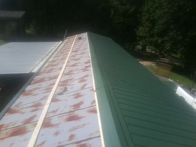 Old rusted panels beside newly installed green metal roofing — Wind Damage Roof Repair by Roofing Brothers in Mentor