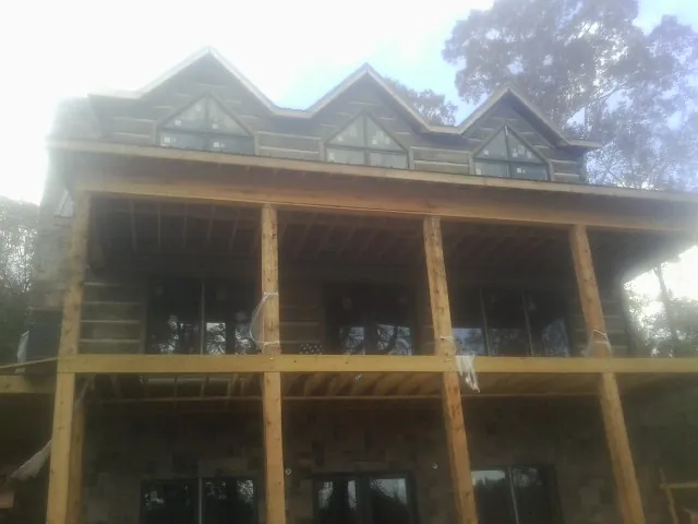 Dormers and porch framing on a large log home under construction — Roof Coating work by our crew in Mentor