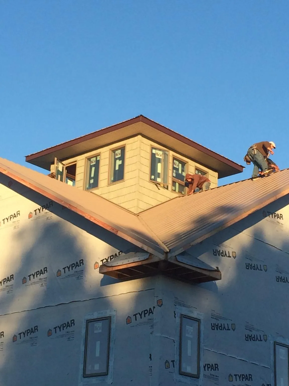 Roofers working around a rooftop cupola on a new metal roof at sunset — Roof Waterproofing in Mentor by Roofing Brothers